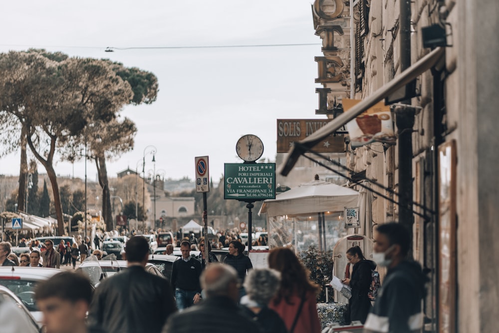 a crowd of people walking down a street next to tall buildings