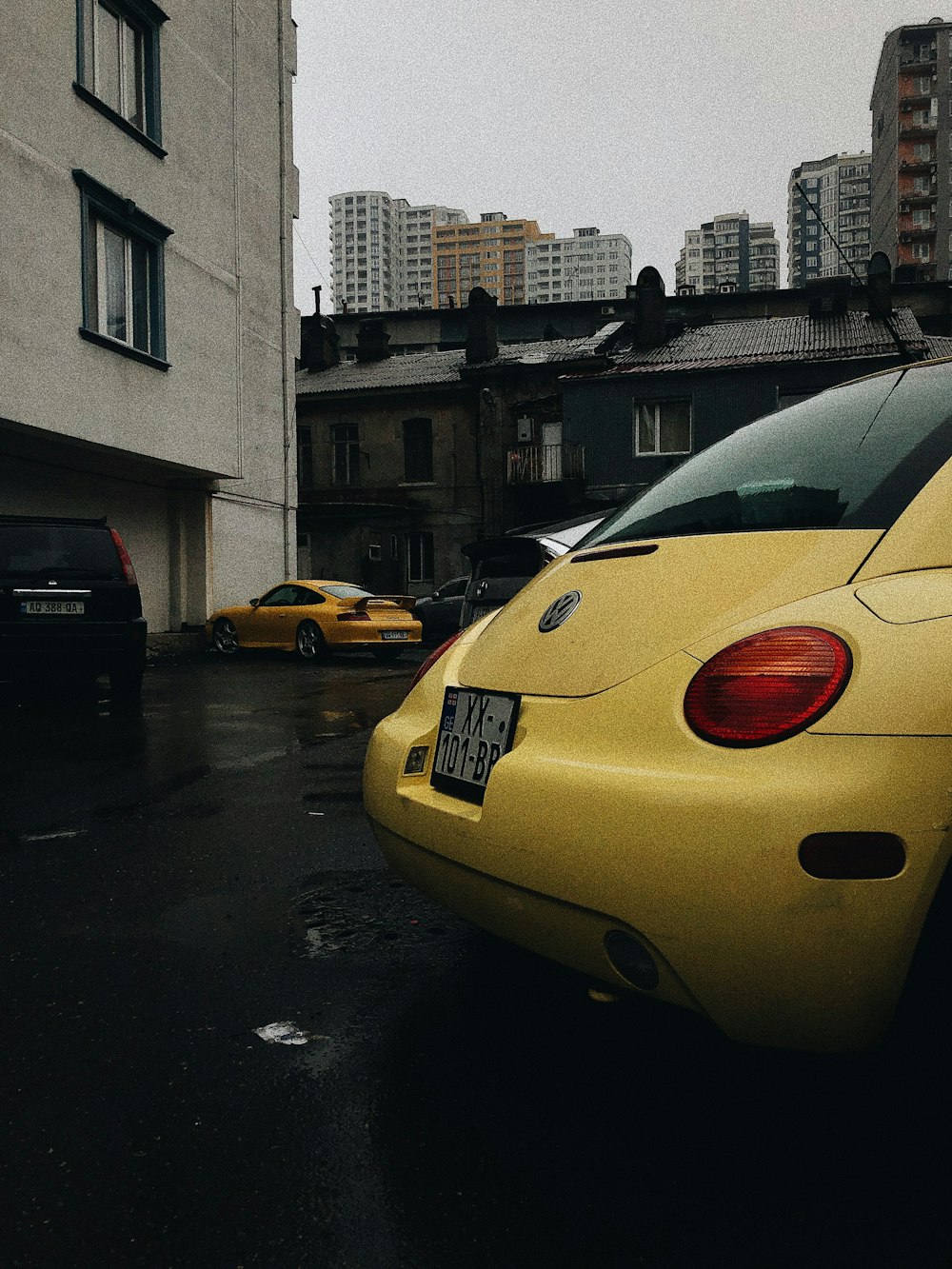 a yellow car parked in a parking lot next to a tall building