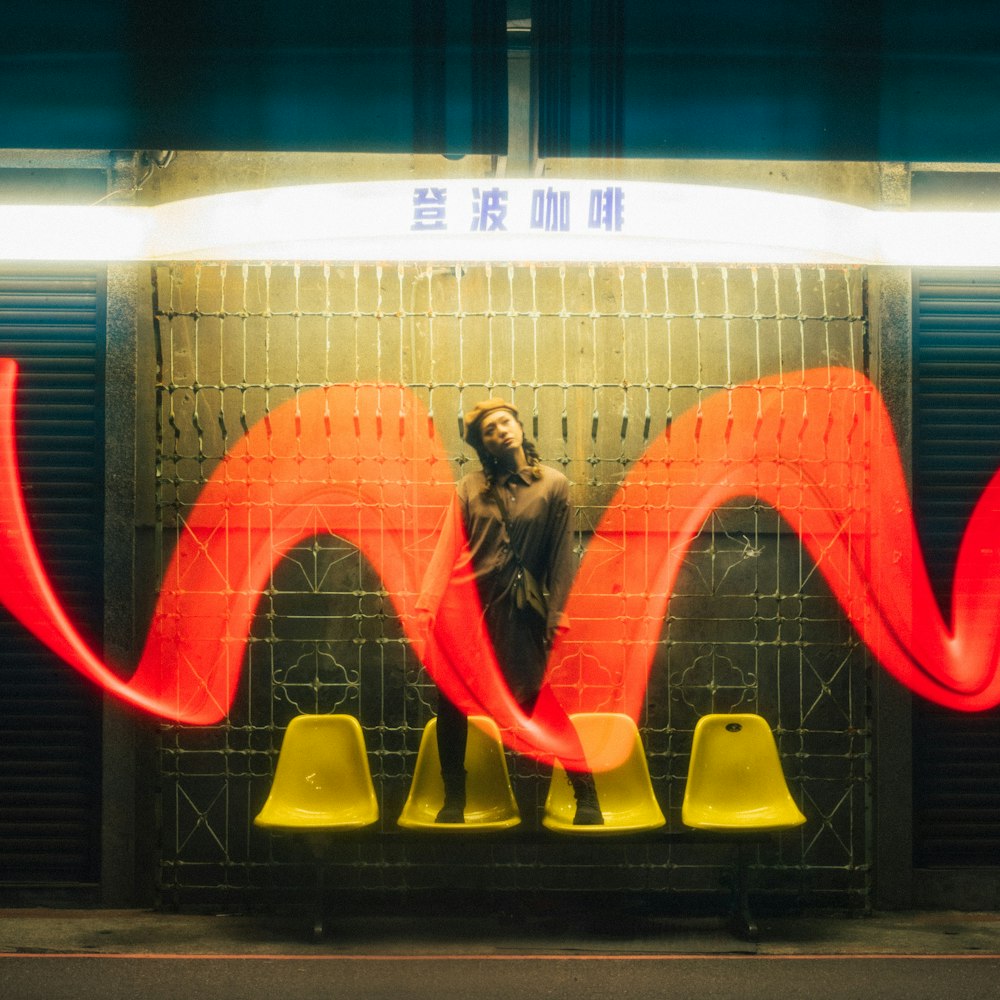 Une femme debout devant un mur avec une vague rouge dessus