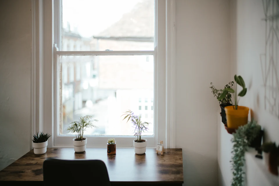 A simple desk and chair with a potted plant in window light