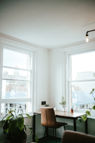 a room with a desk, chair and two windows
