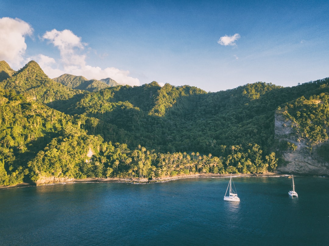 a couple of boats floating on top of a large body of water, Sailing yachts in front of a Caribbean island.