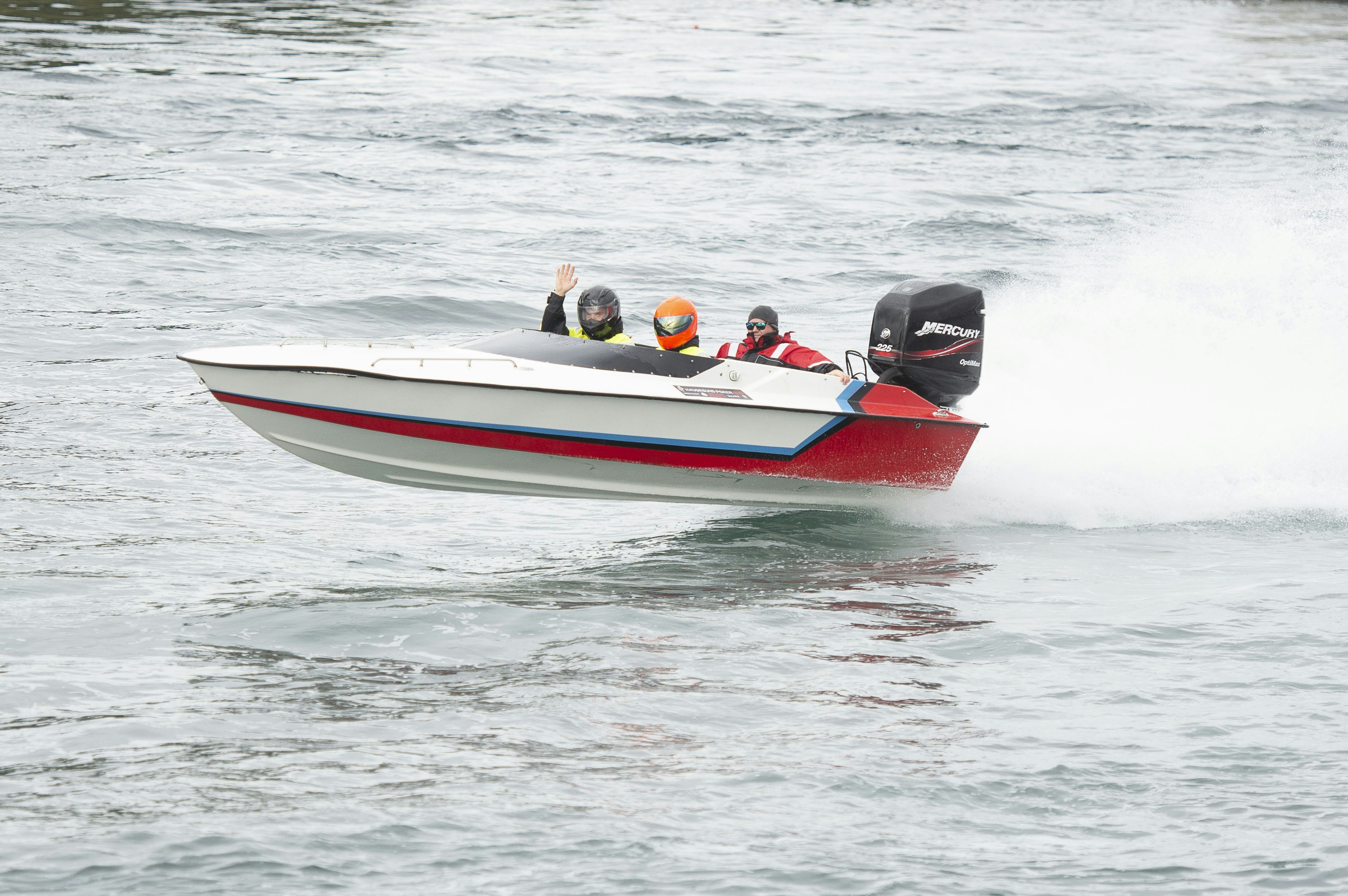 A man riding on the back of a red and white boat photo – Free Brown ...