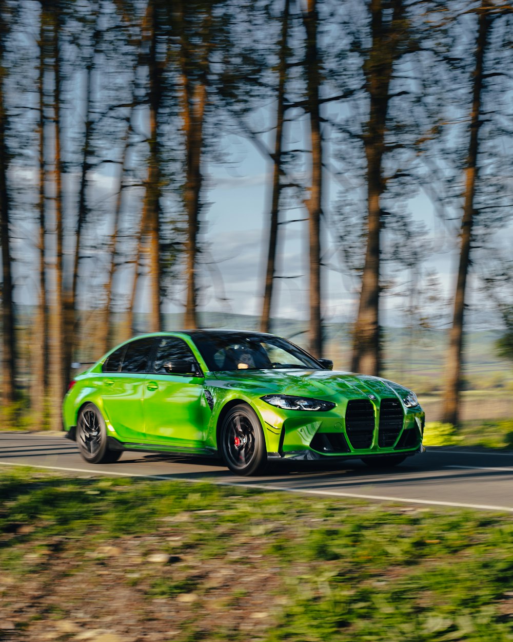 a green sports car driving down a country road
