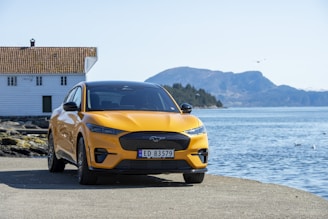 A bright, cheerful rental car parked near Victoria's waterfront with mountains in the background.