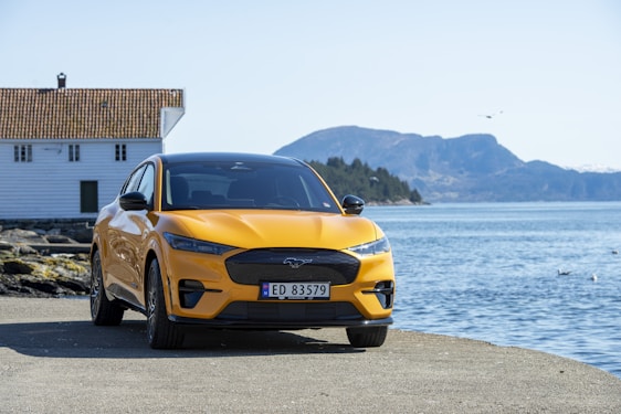 A bright, cheerful rental car parked near Victoria's waterfront with mountains in the background.