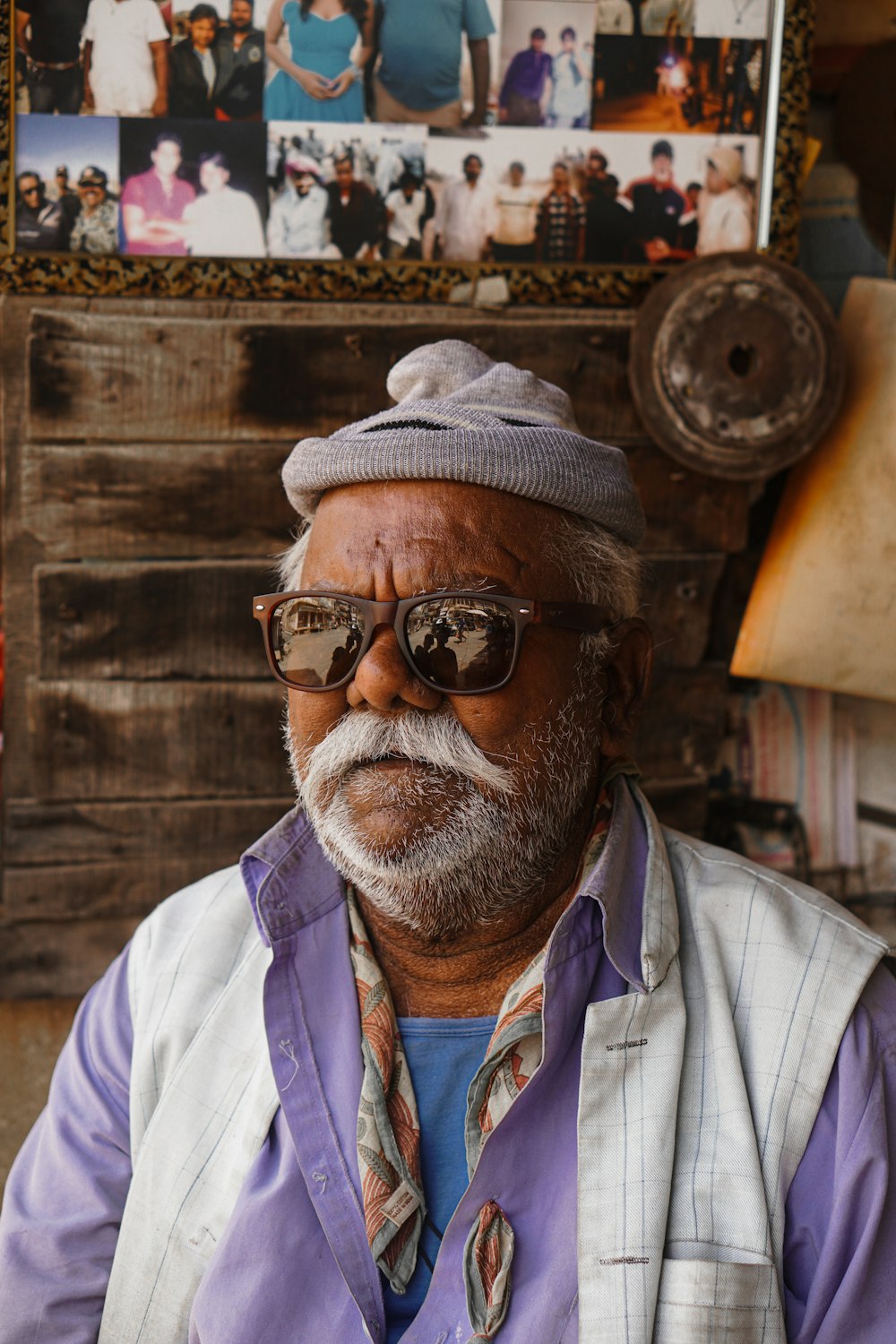 a man with a hat and sunglasses sitting in front of a picture