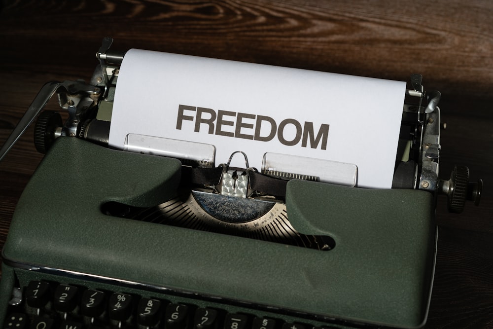 a typewriter with a paper that reads freedom on it