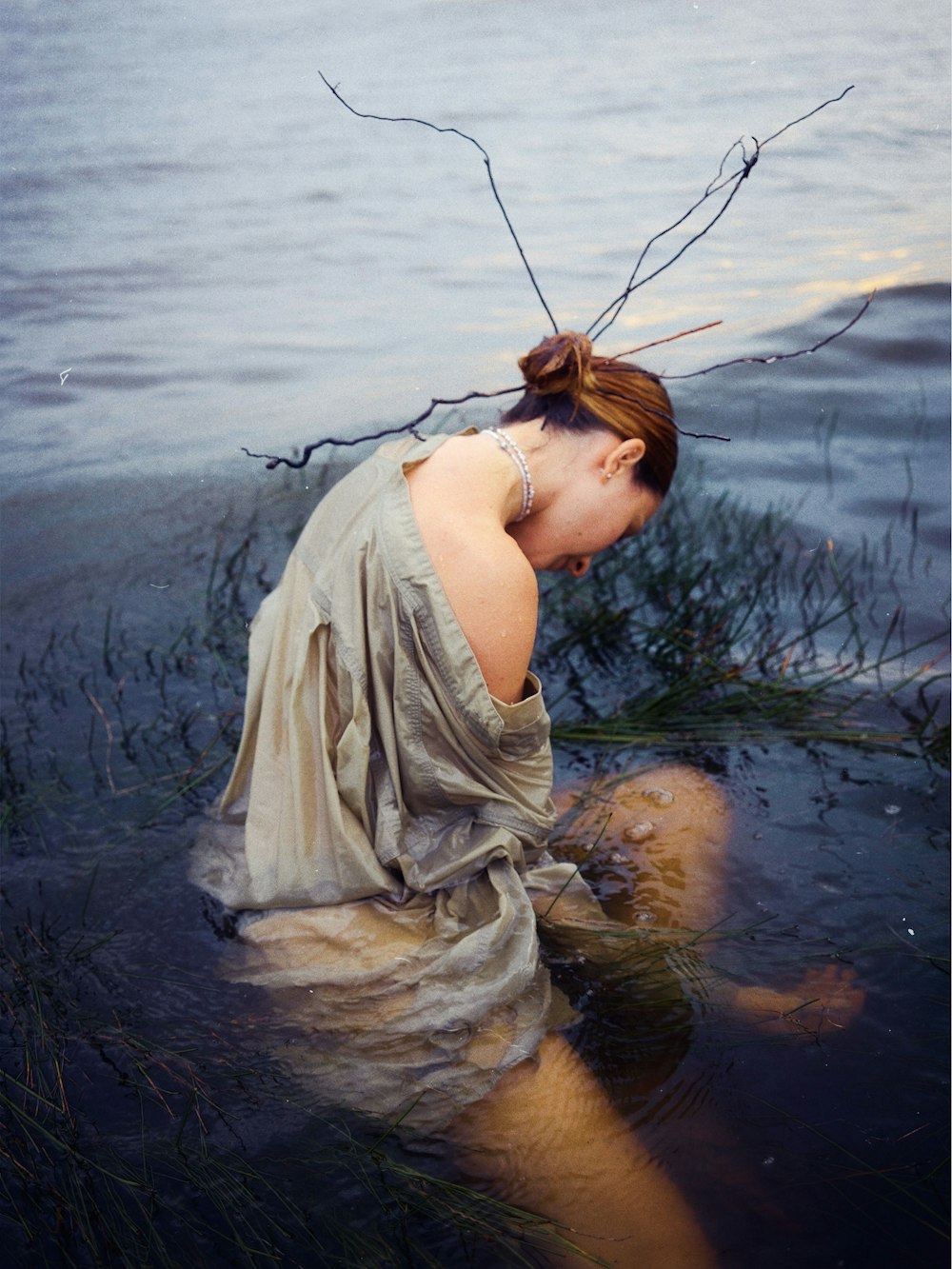 a woman sitting in the water with her head in her hands