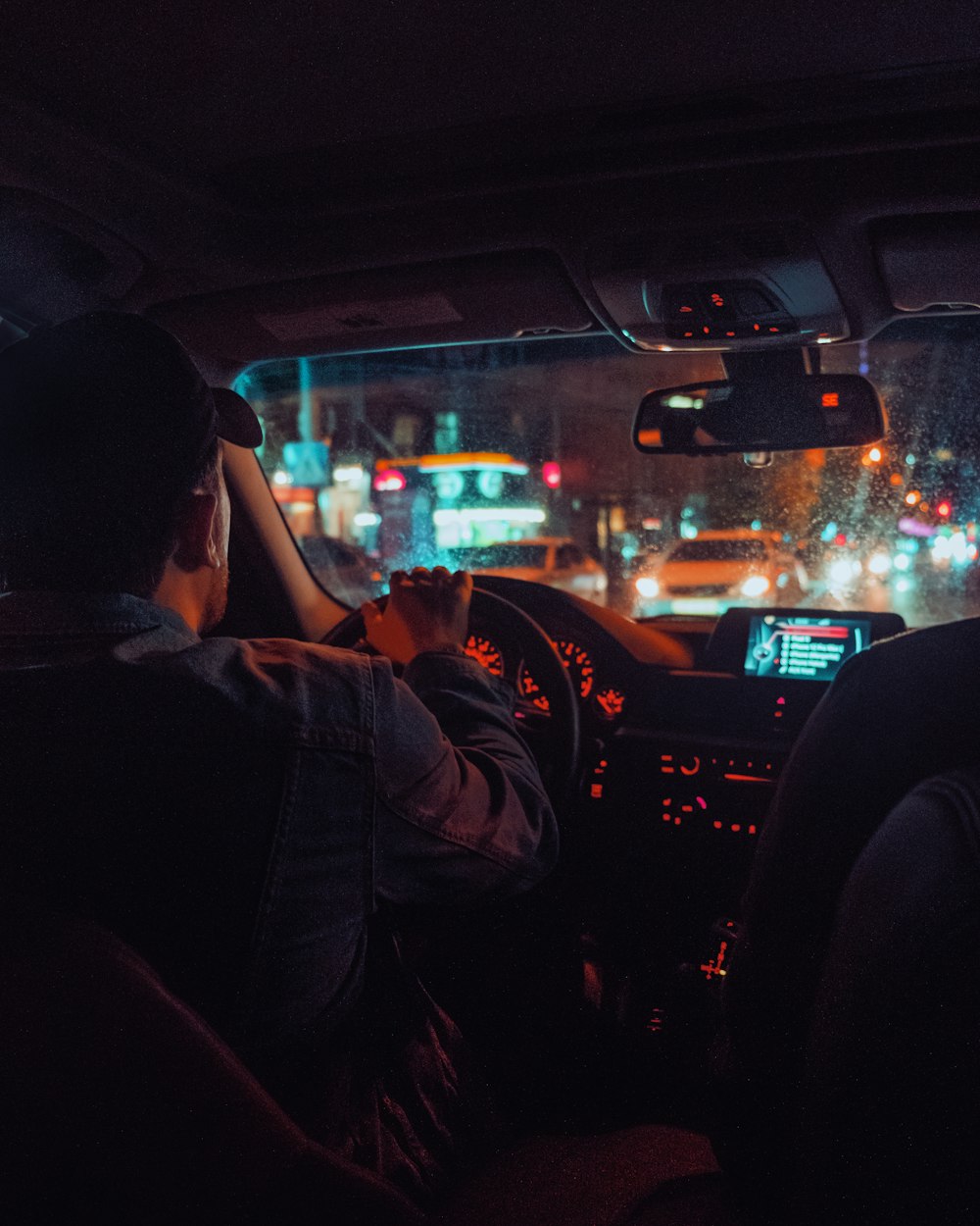 a man driving a car at night in the city