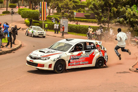 A diverse group of students practicing driving maneuvers in a sunny African neighborhood.