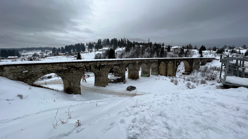 uma estrada coberta de neve com uma ponte no fundo
