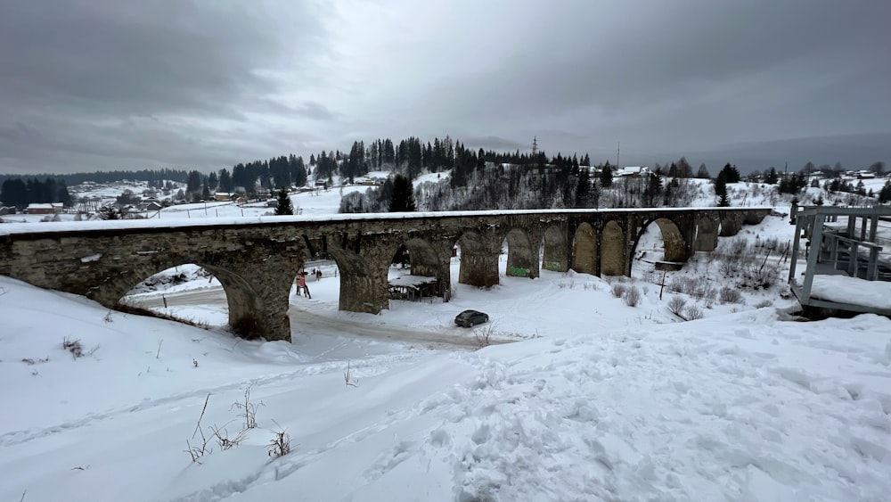 a snow covered road with a bridge in the background