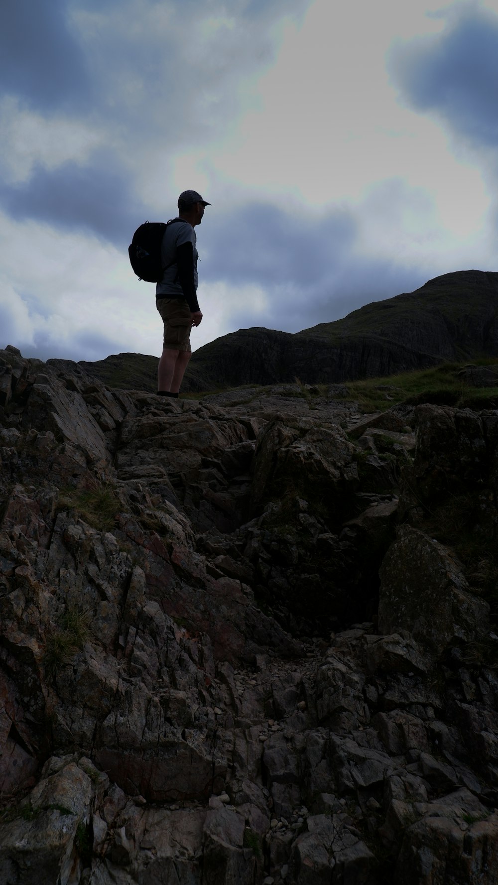 a man with a backpack standing on top of a rocky hill