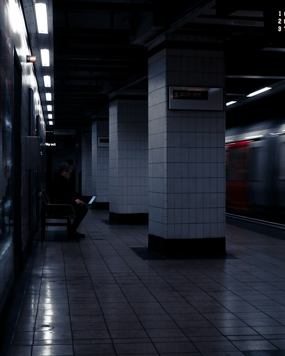 a man sitting on a bench in a subway station