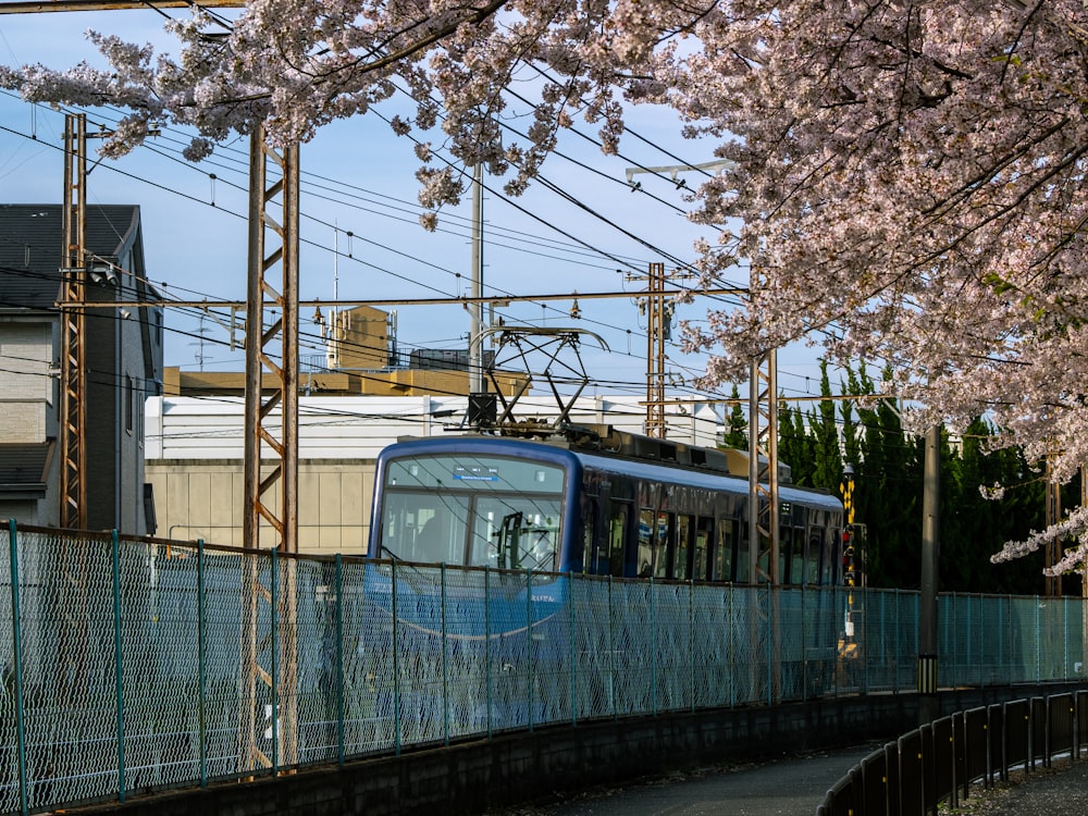 um trem azul e branco em uma pista ao lado de uma cerca