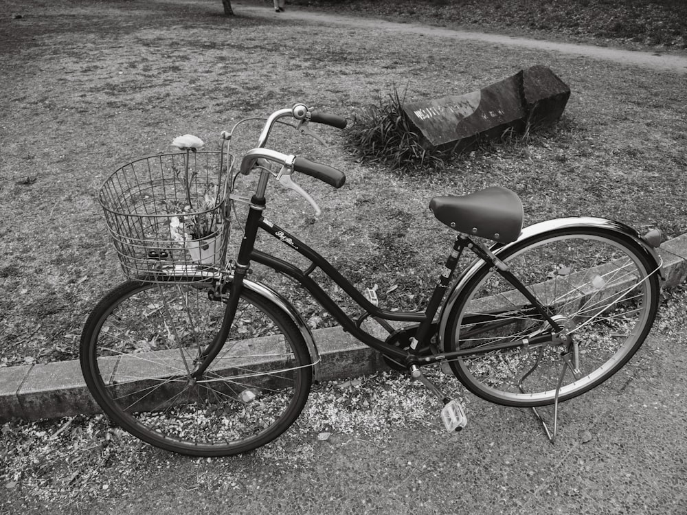 a black and white photo of a bicycle parked on a curb
