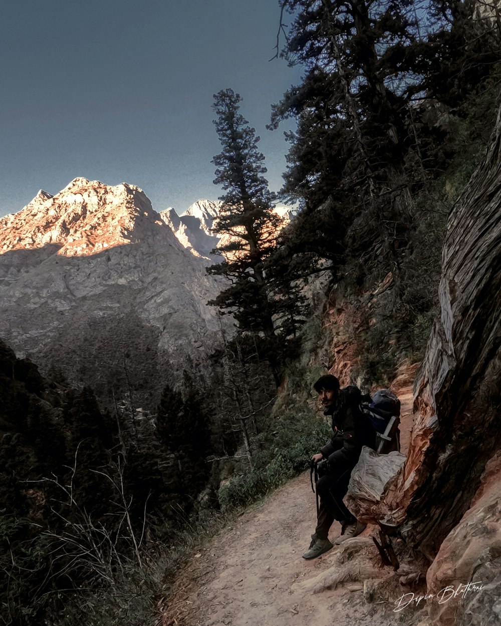 a man hiking up a trail in the mountains