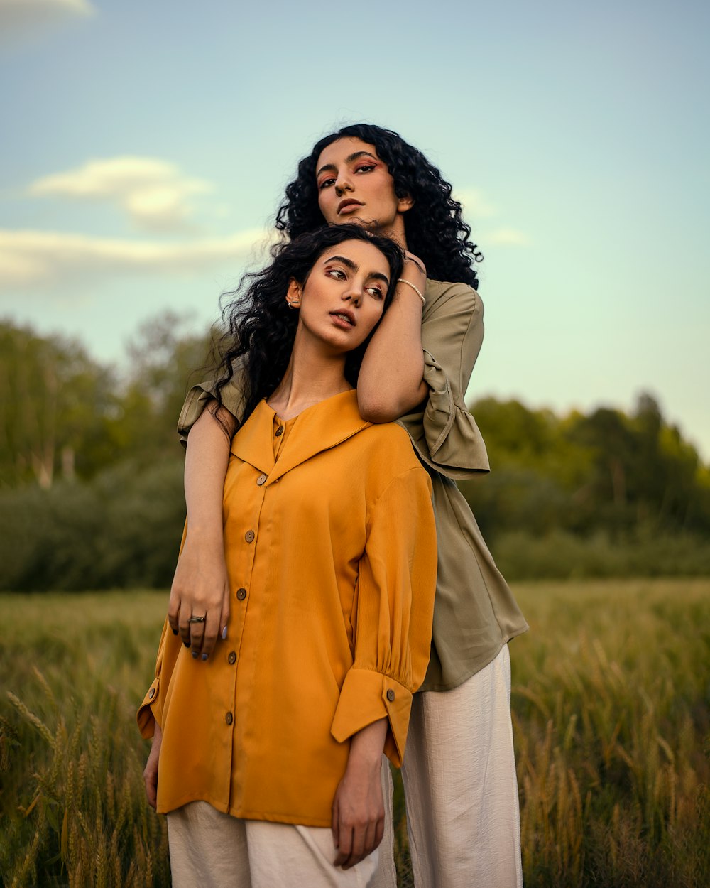 a couple of women standing next to each other in a field