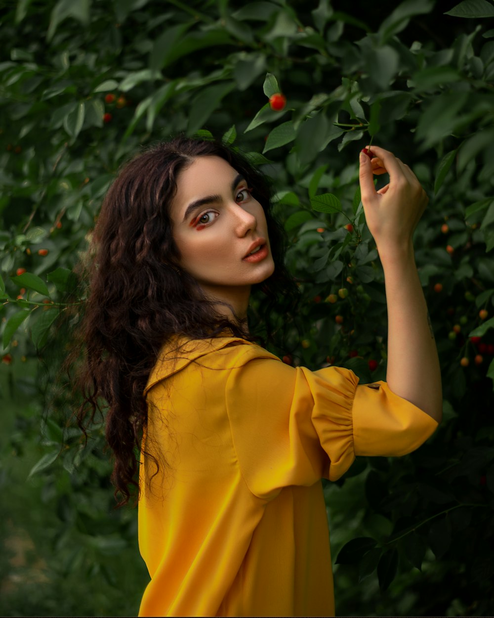 a woman in a yellow dress is picking fruit off a tree