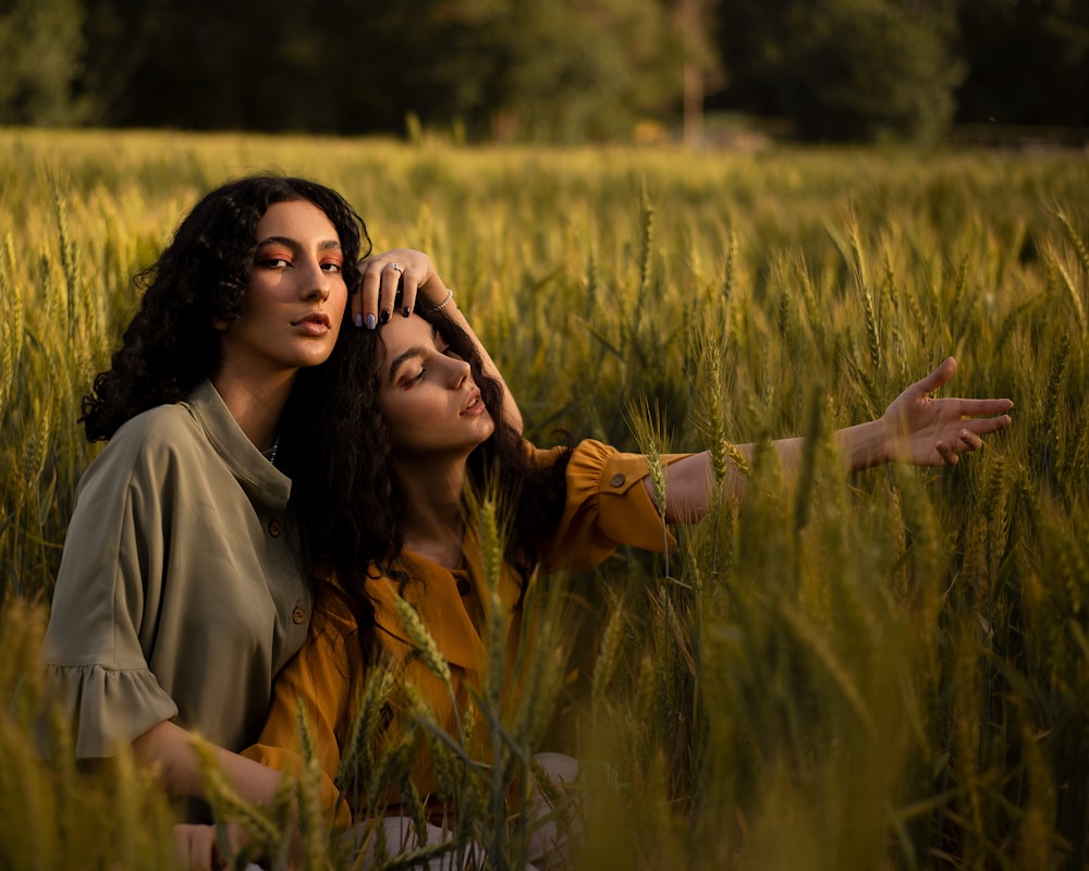 a couple of women standing in a field of tall grass