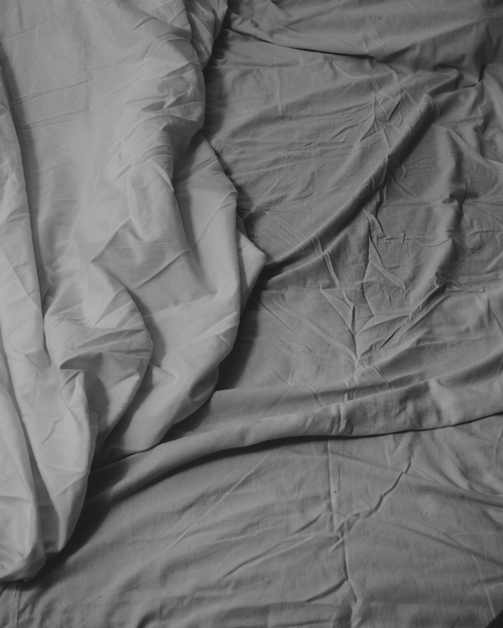 a black and white photo of a messy bed