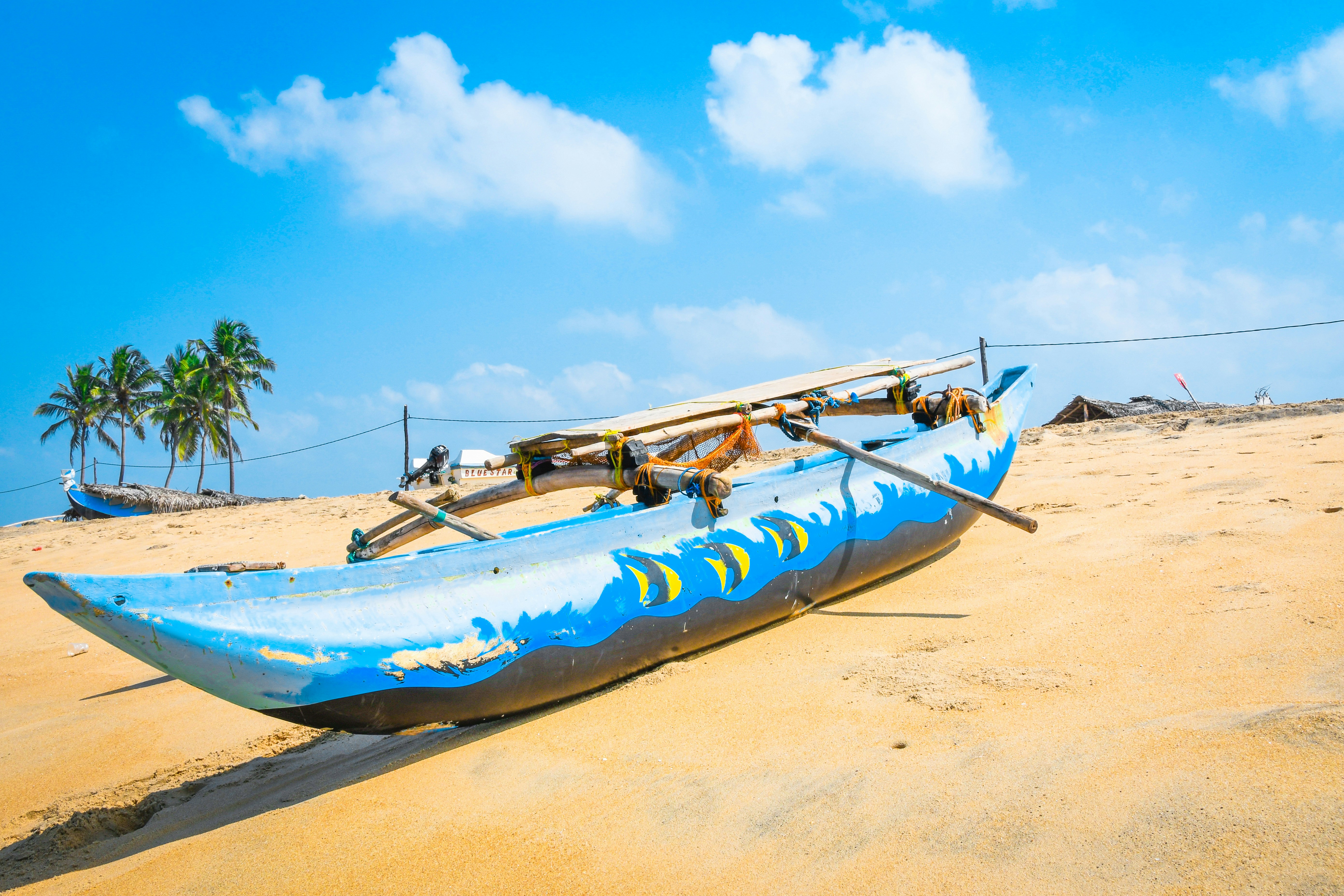 a blue boat sitting on top of a sandy beach