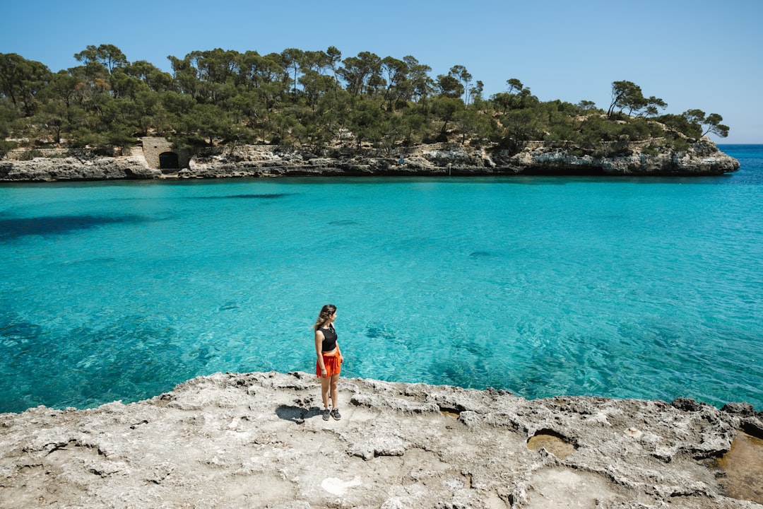 a woman standing on a cliff overlooking the ocean, Blue ass water