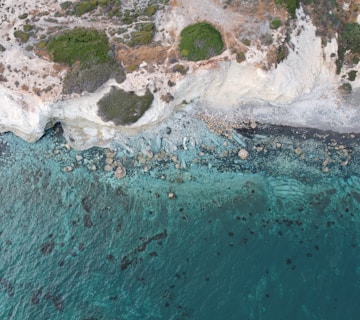 an aerial view of an ocean with rocks and water