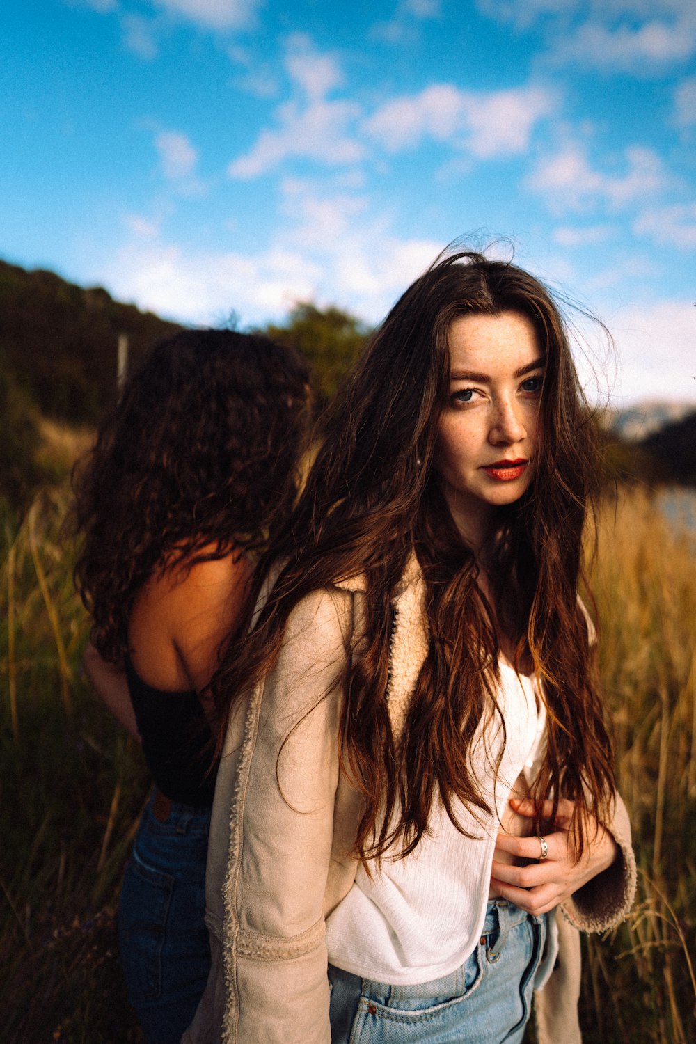 two young women standing next to each other in a field