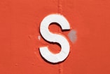 a close up of a white letter s on an orange wall