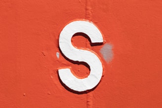a close up of a white letter s on an orange wall
