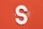 a close up of a white letter s on an orange wall
