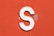 a close up of a white letter s on an orange wall