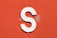 a close up of a white letter s on an orange wall