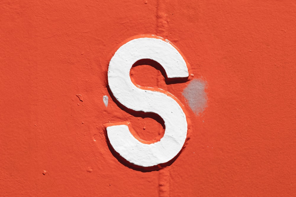 a close up of a white letter s on an orange wall