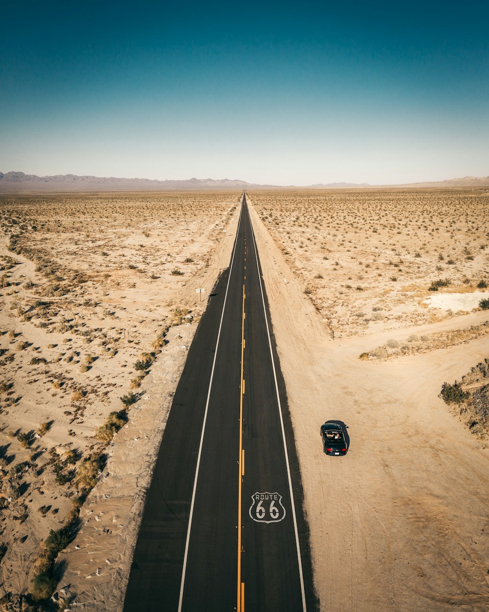 a car driving down a road in the middle of the desert