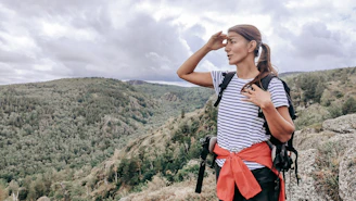 a woman standing on top of a mountain with a backpack
