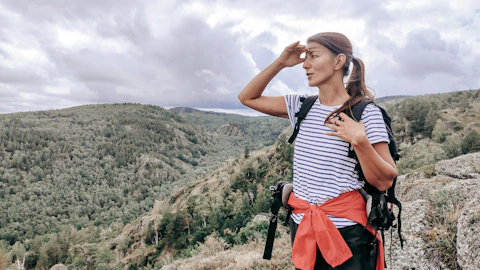 a woman standing on top of a mountain with a backpack