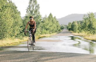 a woman riding a bike down a wet road