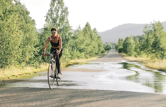 a woman riding a bike down a wet road