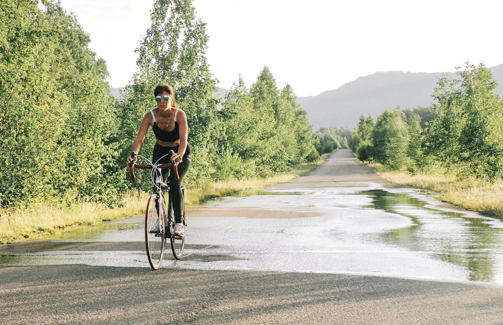 a woman riding a bike down a wet road