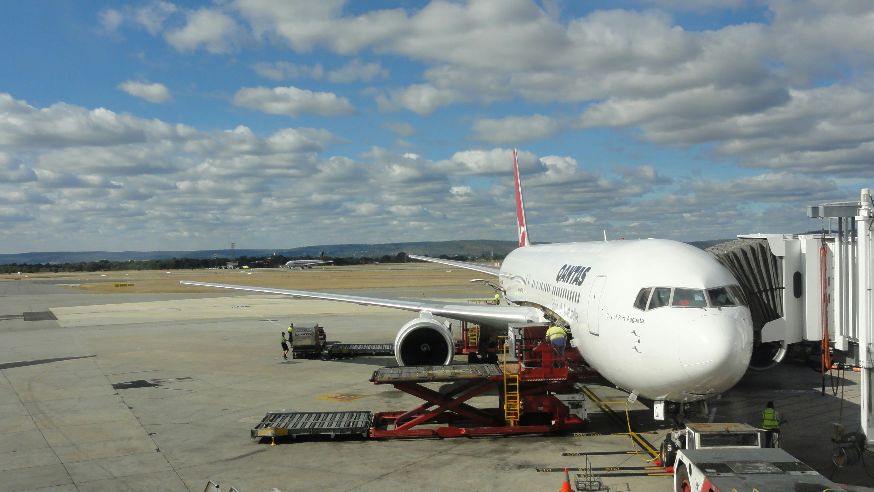 a large jetliner sitting on top of an airport tarmac, Cargo loading on Qantas flight</p><p>