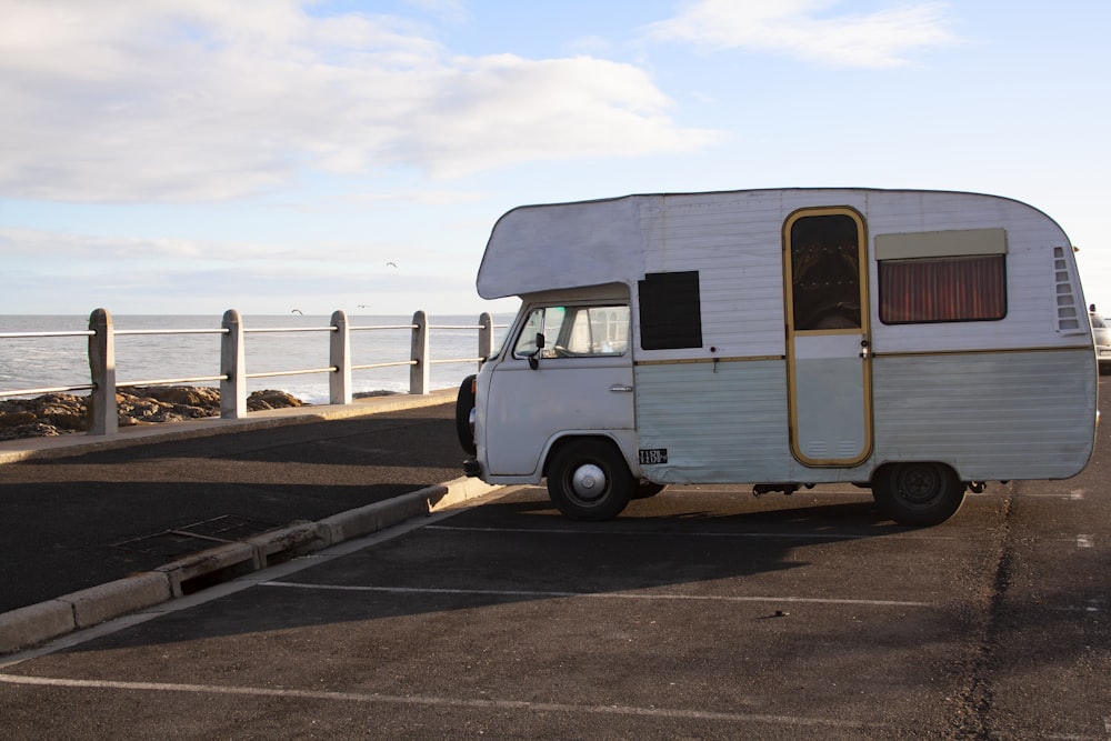 a white trailer parked in a parking lot next to the ocean