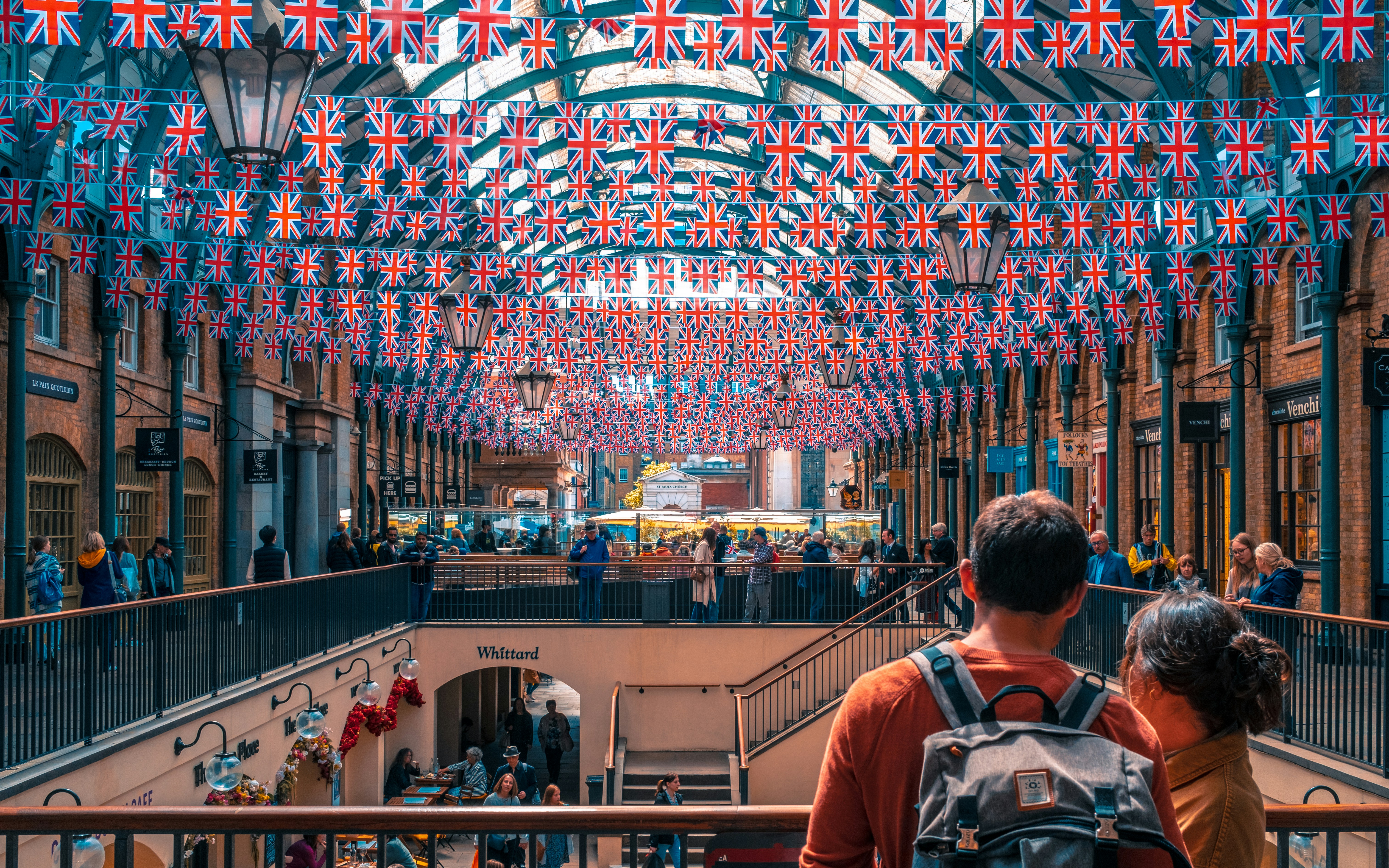 a group of people standing in a building with flags hanging from the ceiling