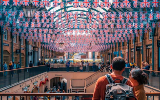 a group of people standing in a building with flags hanging from the ceiling