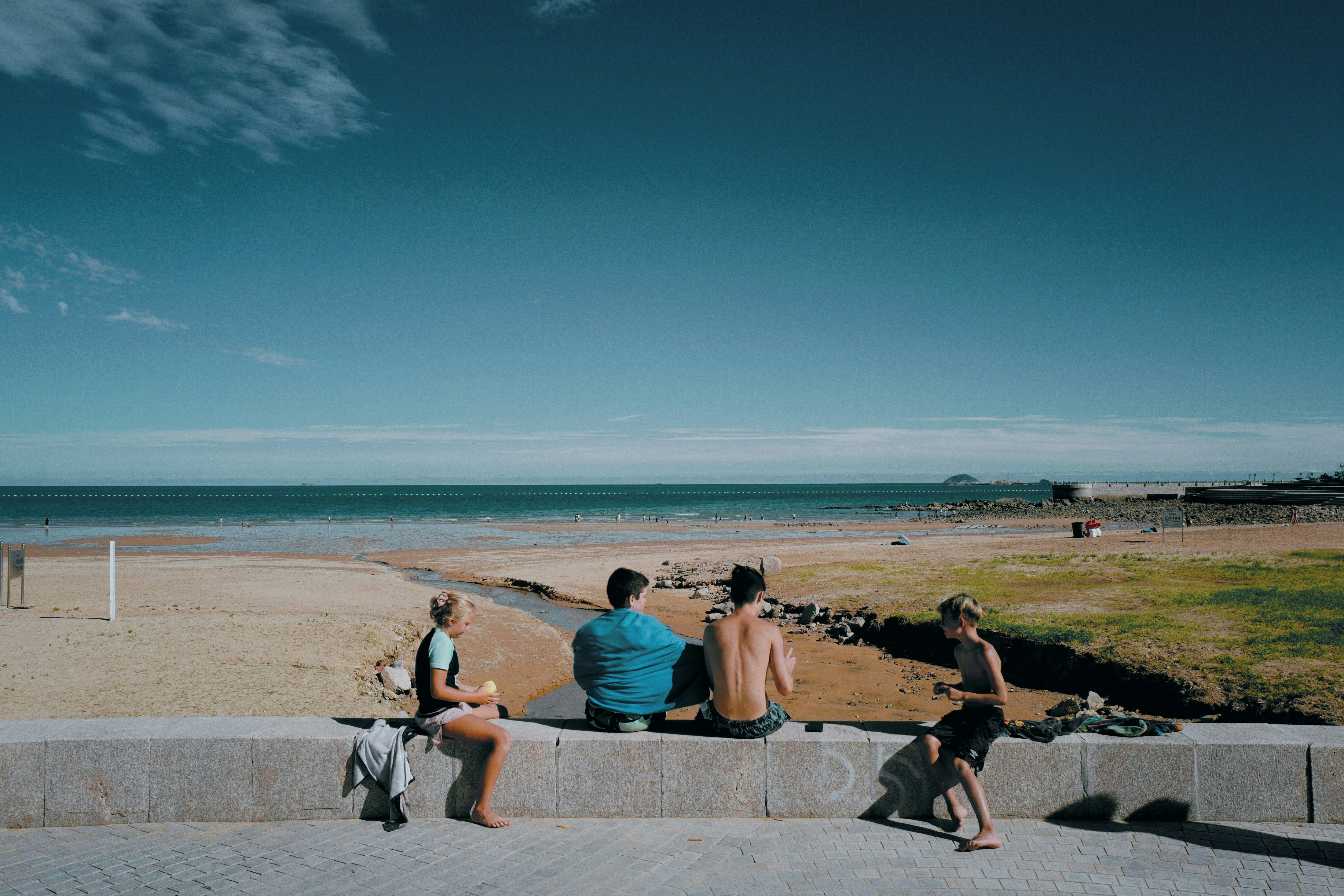 a group of people sitting on top of a cement wall