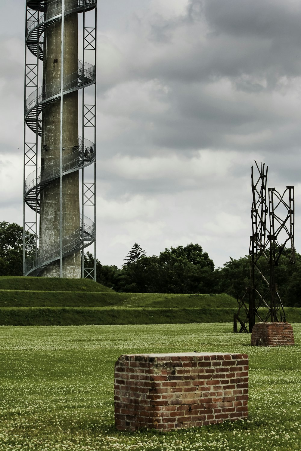 a tall tower next to a brick wall in a field