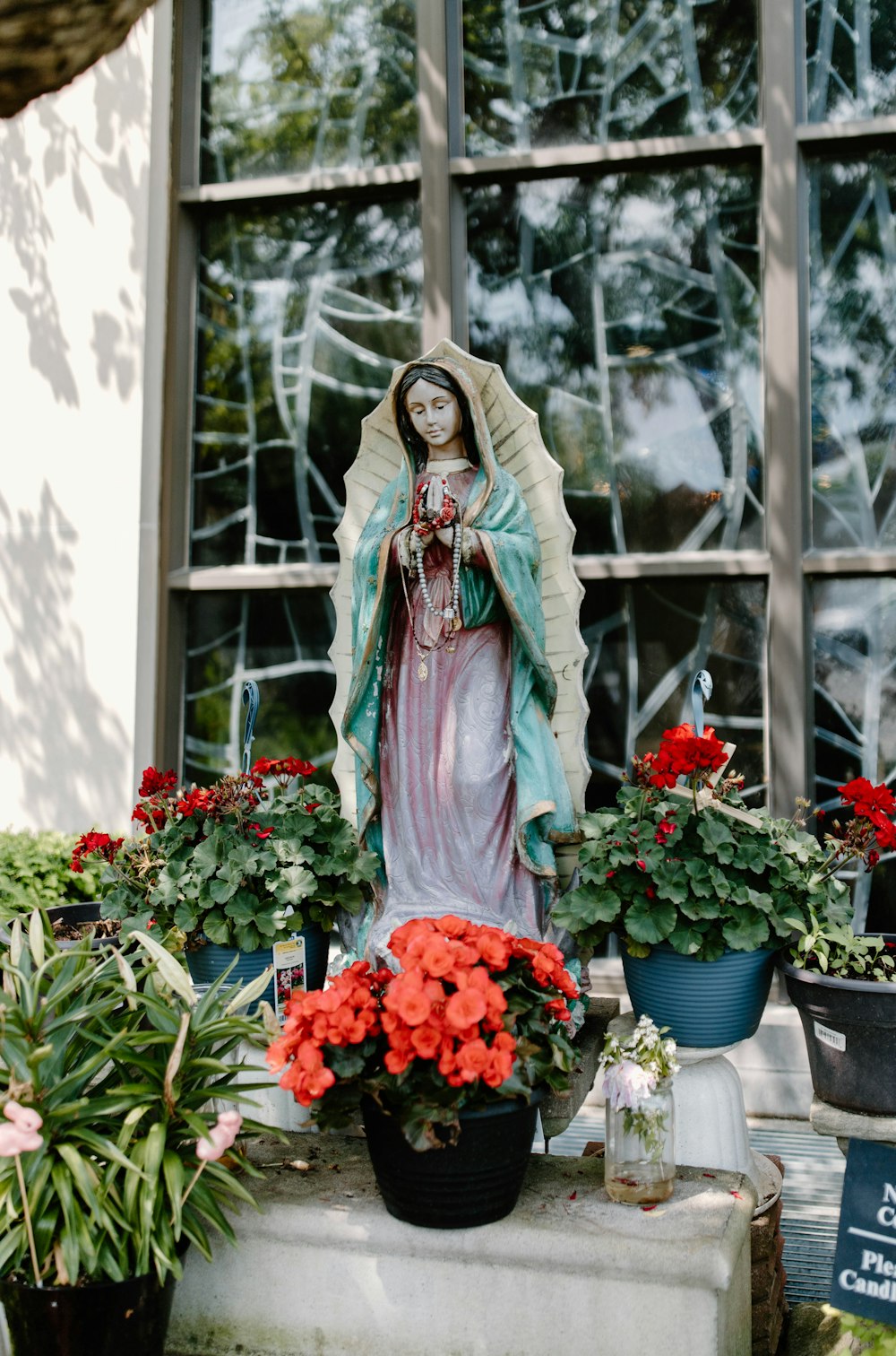 a statue of the virgin mary surrounded by potted flowers