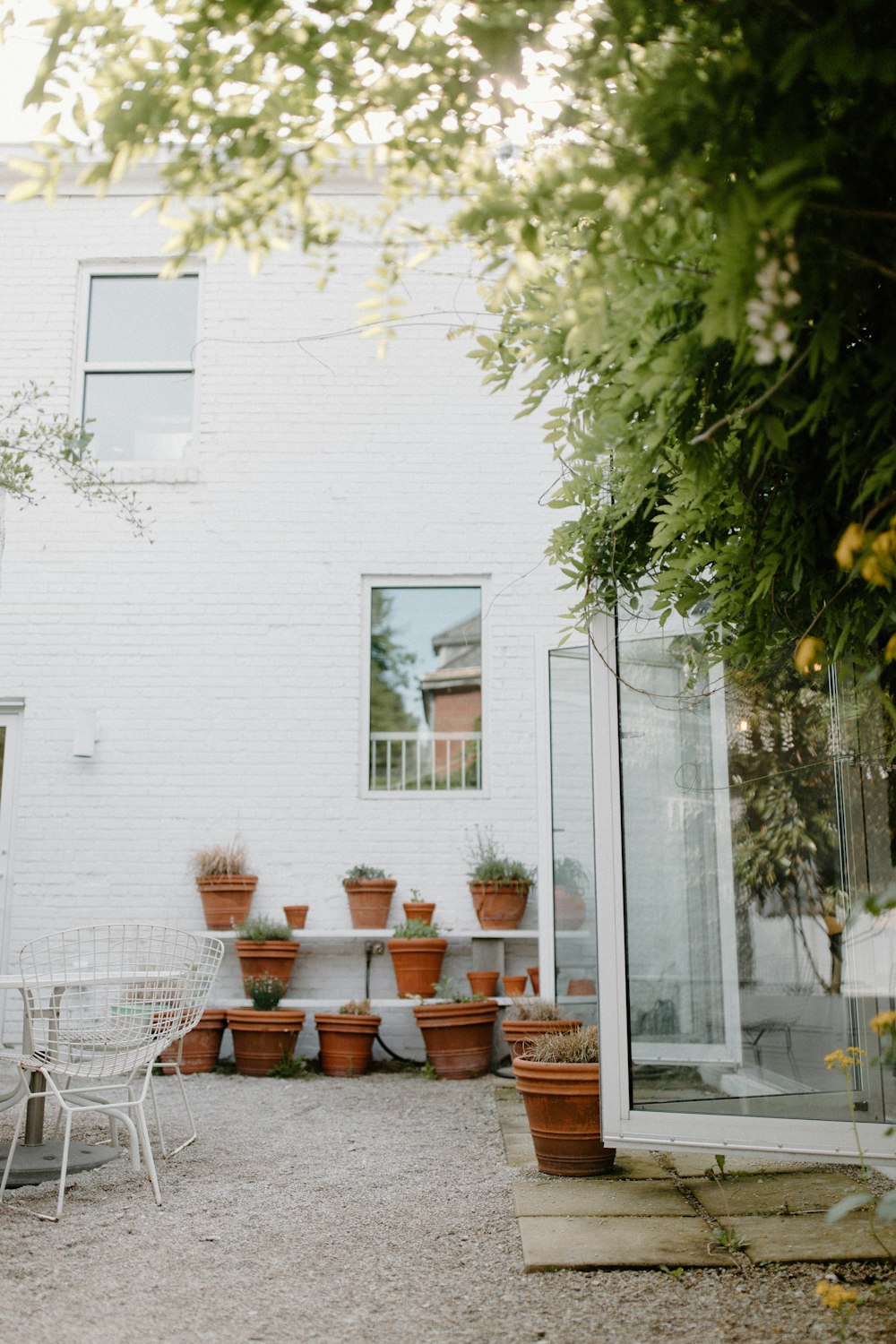 uma casa branca com vasos de plantas no pátio